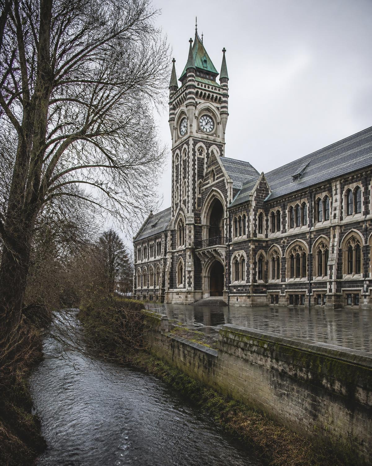 The bluestone Gothic Revival clocktower building at Otago beside the Leith stream on a wet southern day